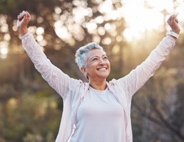 a woman with dentures smiling while exercising outside