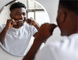 Man smiling in mirror while flossing 