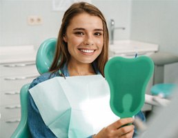 A woman admiring her smile in a hand mirror