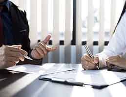 Two people sitting at table, reviewing paperwork