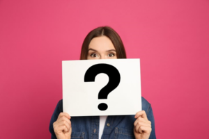 Woman on hot pink background holding up sign with question mark